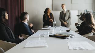  Documents and diaries at desk with business colleagues during meeting in office