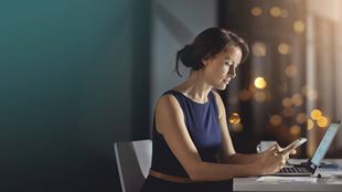 femme avec téléphone et ordinateur portable au bureau