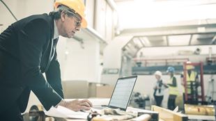 business man with construction hat looking at laptop