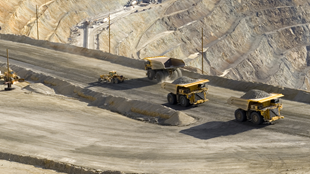 A line of trucks in a mine transporting rock