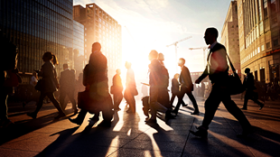 People walking in street with sun behind