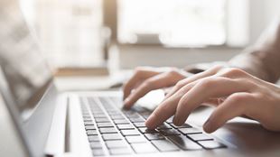 closeup of fingers typing on laptop
