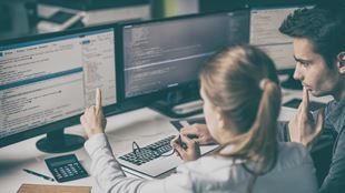 two people discussing at computer station
