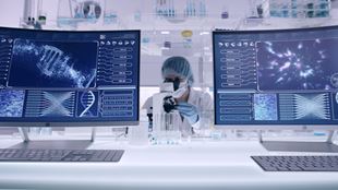  Female studying DNA samples. Computer screens with DNA sequences. Scientist examines DNA models in modern Genetic Research Laboratory. Looking through laboratory glassware