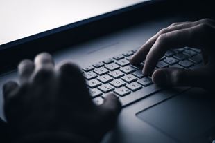 Hacker's hands typing on a keyboard at night