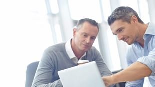 two men staring at laptop