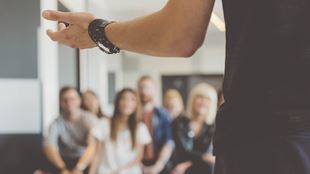 back view of and arm of person speaking to a group of people