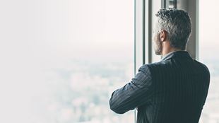 homme regardant par la fenêtre avec les bras croisés