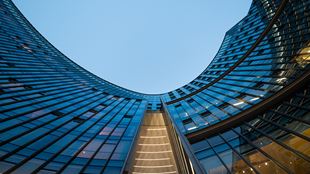  Illuminated modern curved skyscrapers against clear blue sky at dusk