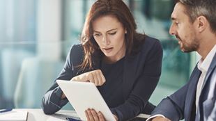 man and woman discussing items on computer tablet