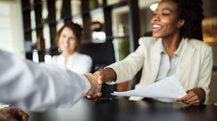 two person are doing a handshake, the women is holding documents