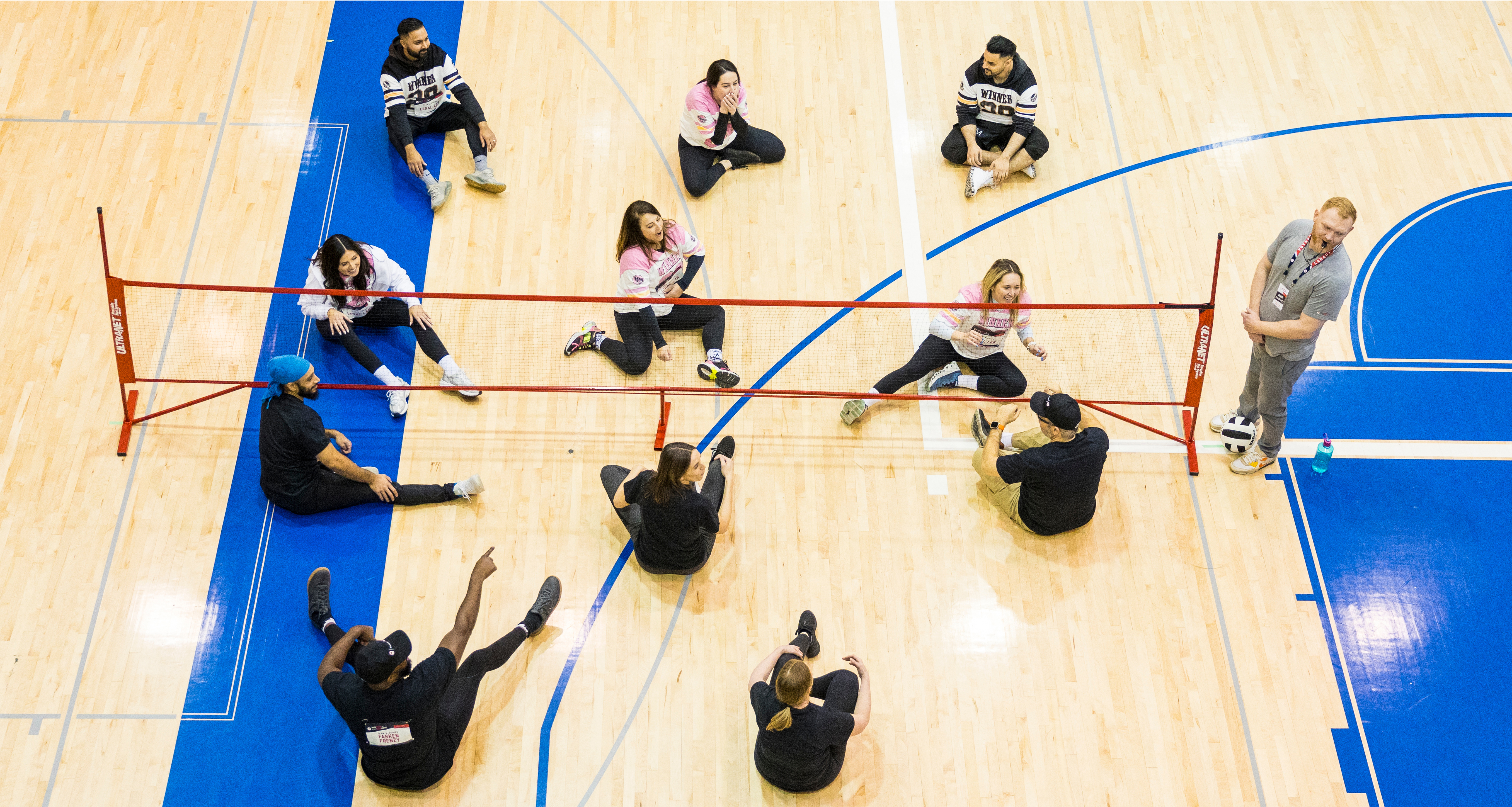 Un groupe d’employés de Fasken jouant au volleyball assis dans un gymnase.