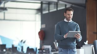 standing man looking at computer tablet in office