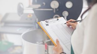 Scientist filling out chart in front of equipment